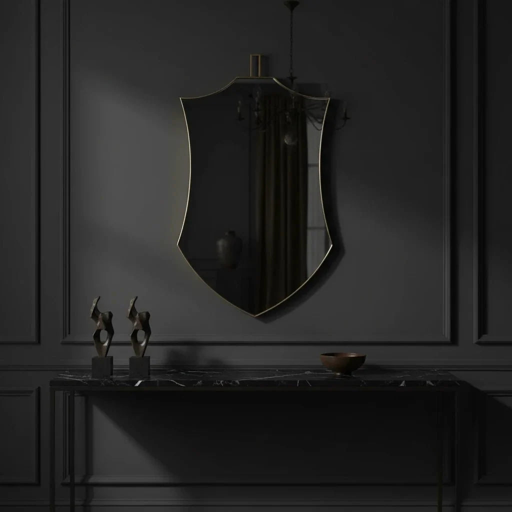Decorative mirror on a dark wall with a console table below featuring sculptures and a bowl.