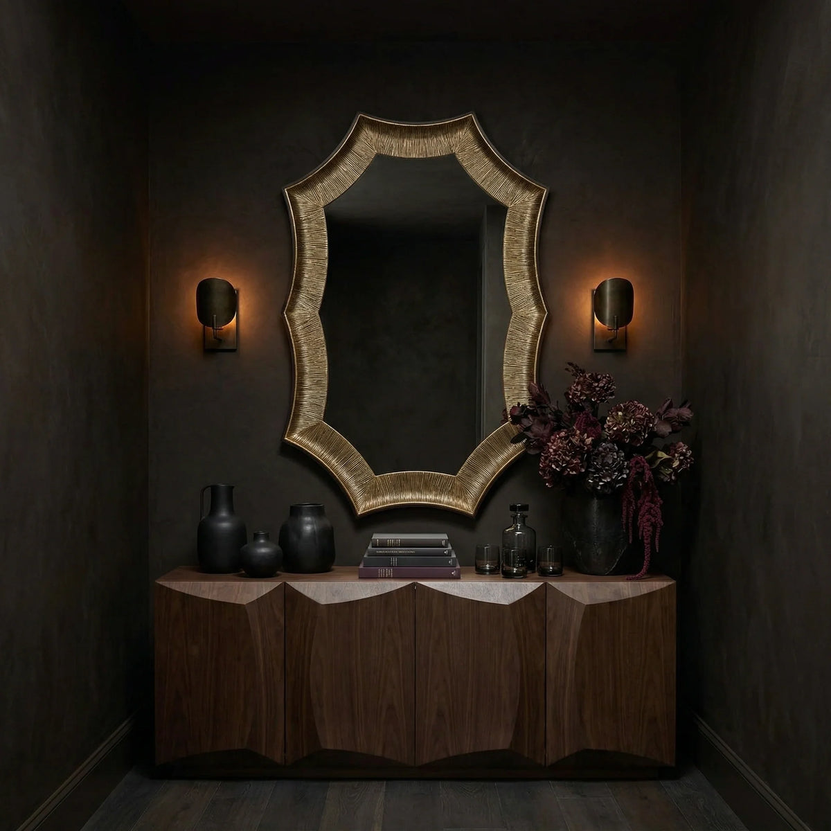 Ambella Home Helios Mirror Large in a sculptural gold finish, oversized statement wall mirror with a faceted organic frame styled above a walnut credenza in a dark luxury hallway