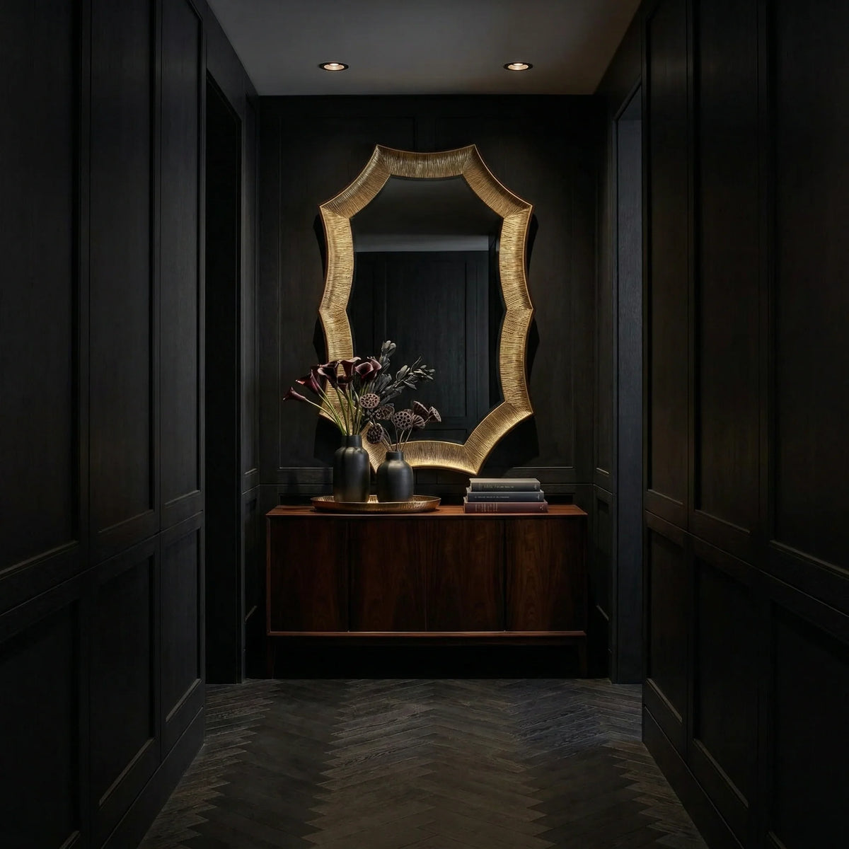 Large Helios Mirror by Ambella Home with a dimensional gilded frame and dramatic silhouette, styled above a wood cabinet in a refined dark foyer with modern sconces and rich decor