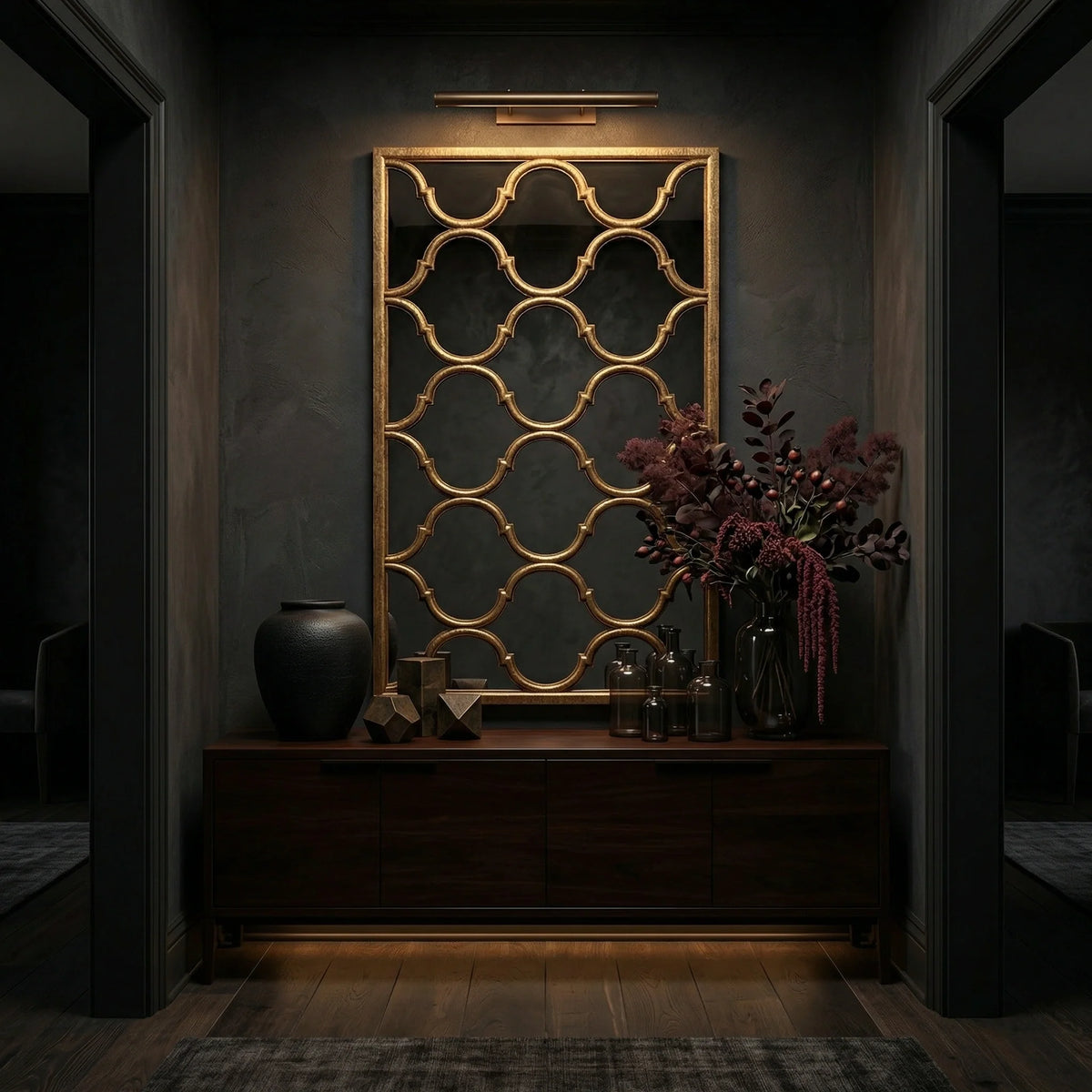 81.5 inch Fret Mirror by Ambella Home with antique wire brush gold finish and geometric open fret design, styled above a dark credenza in a moody interior corridor