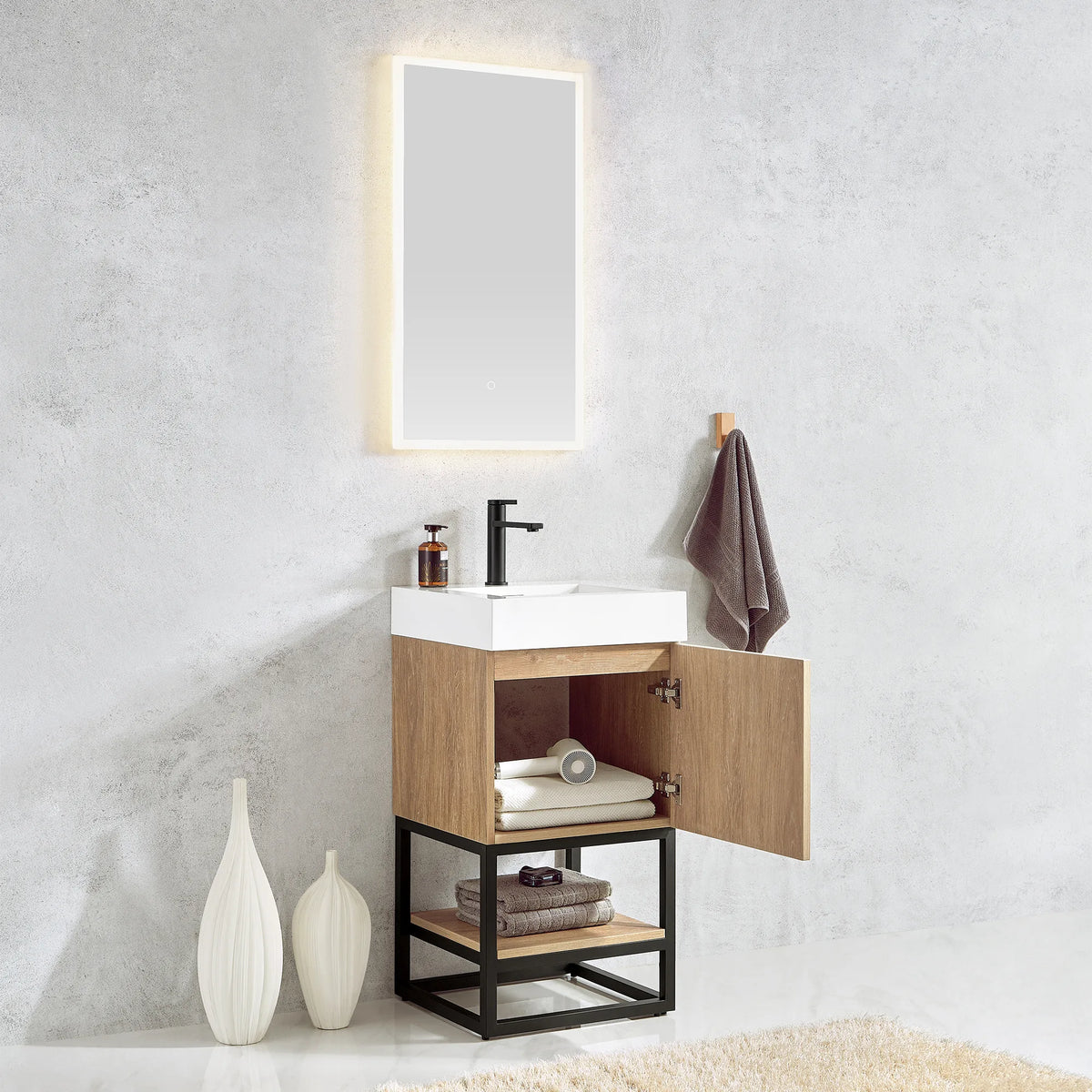 Vanity door standing open over towels, with the lit mirror and wall hook above