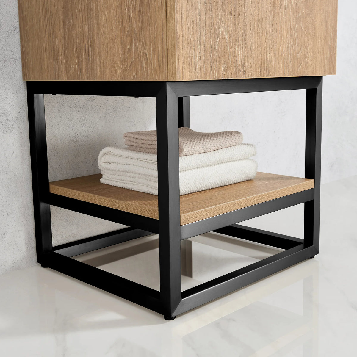 Close-up of the open shelf with folded towels inside the Matte Black metal base