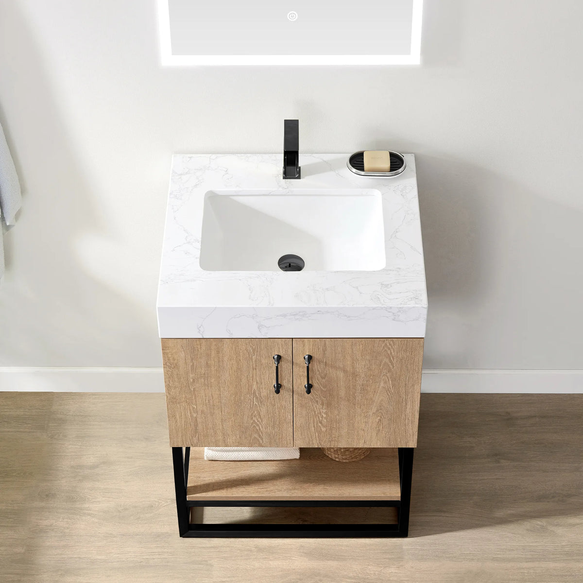 Overhead view of the white grain stone top with its undermount sink, a soap dish and the black door pulls