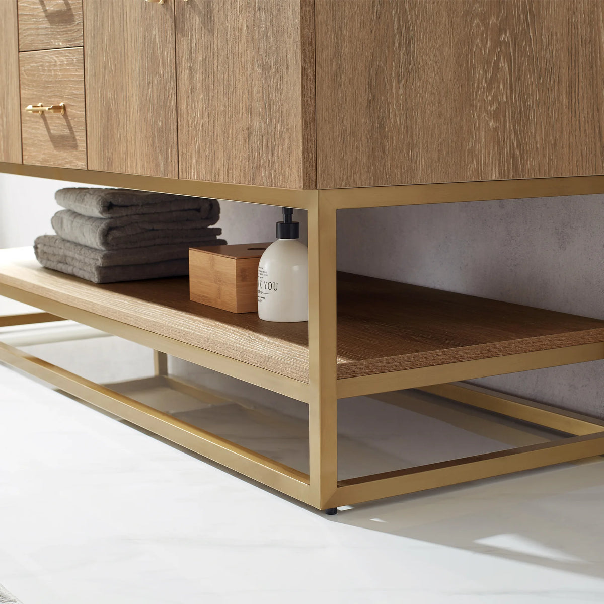 Detail of the double vanity's open shelf with towels, wooden box and soap pump above the gold metal base