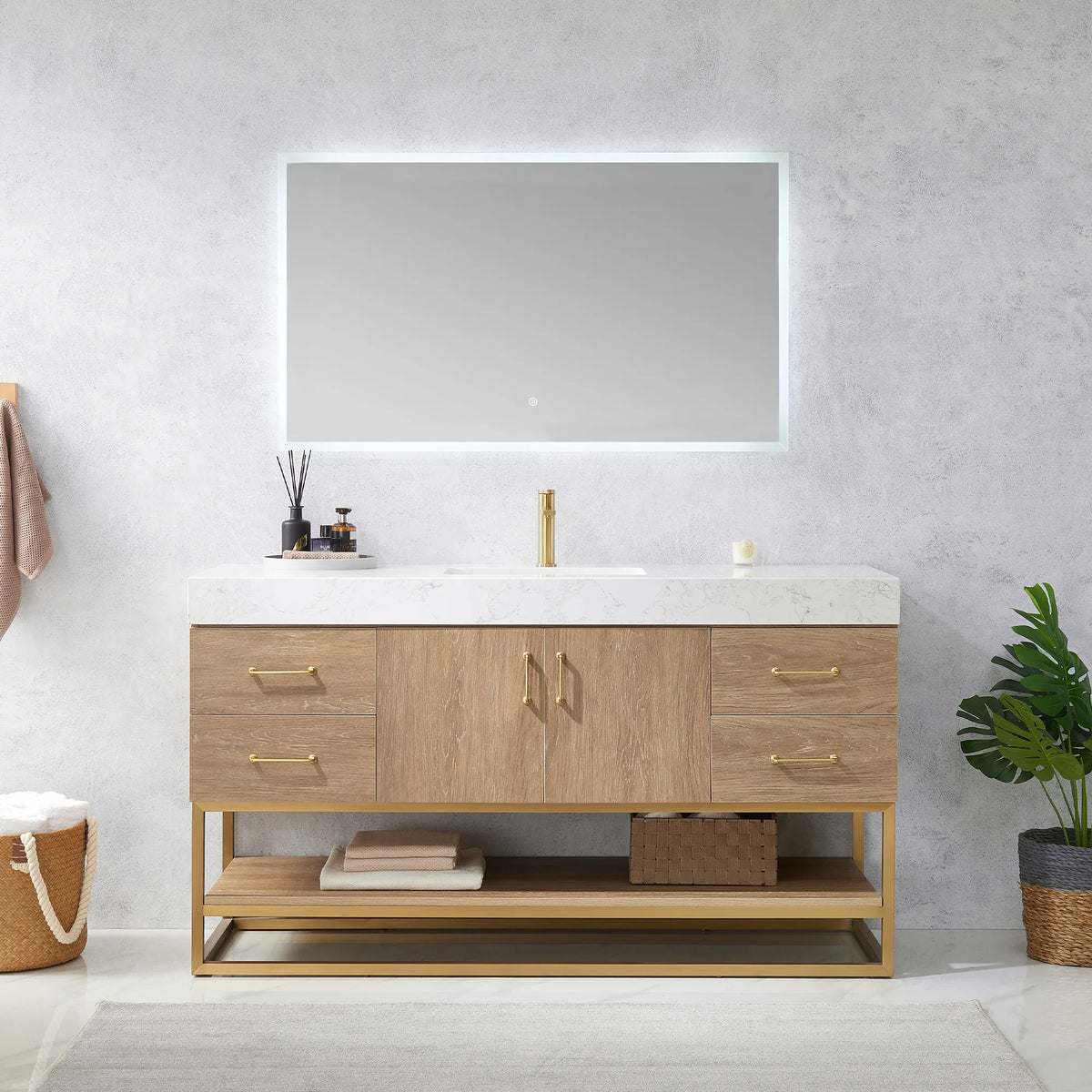 Straight-on view of the vanity beneath an LED mirror, with towel on a hook, woven basket and plant either side