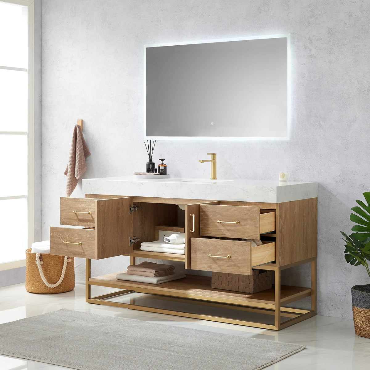 Vanity with drawers and doors open, linens visible inside, mirror above and a plant at right