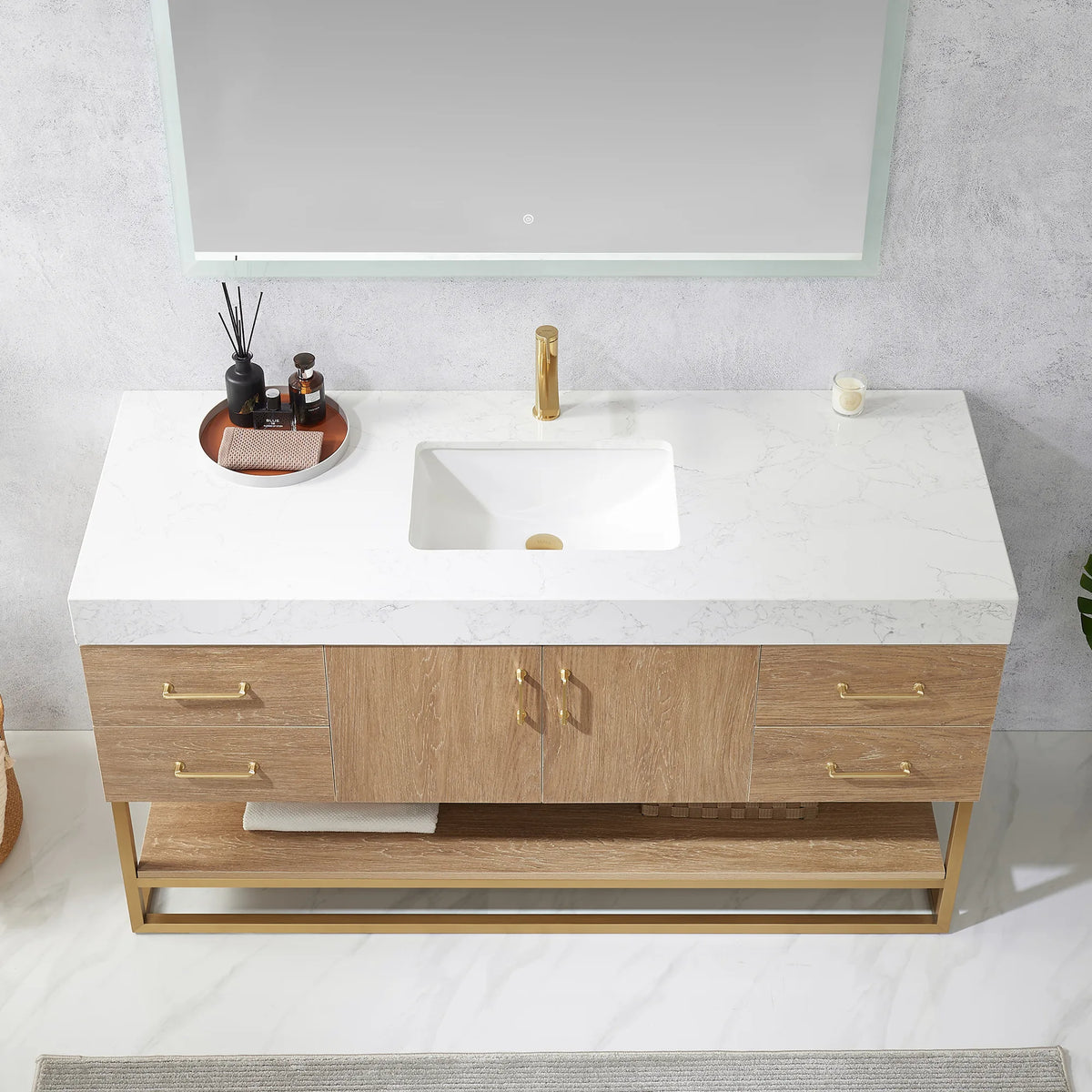 Close-up of the white grain stone countertop and undermount ceramic sink with a decor tray, gold pulls below