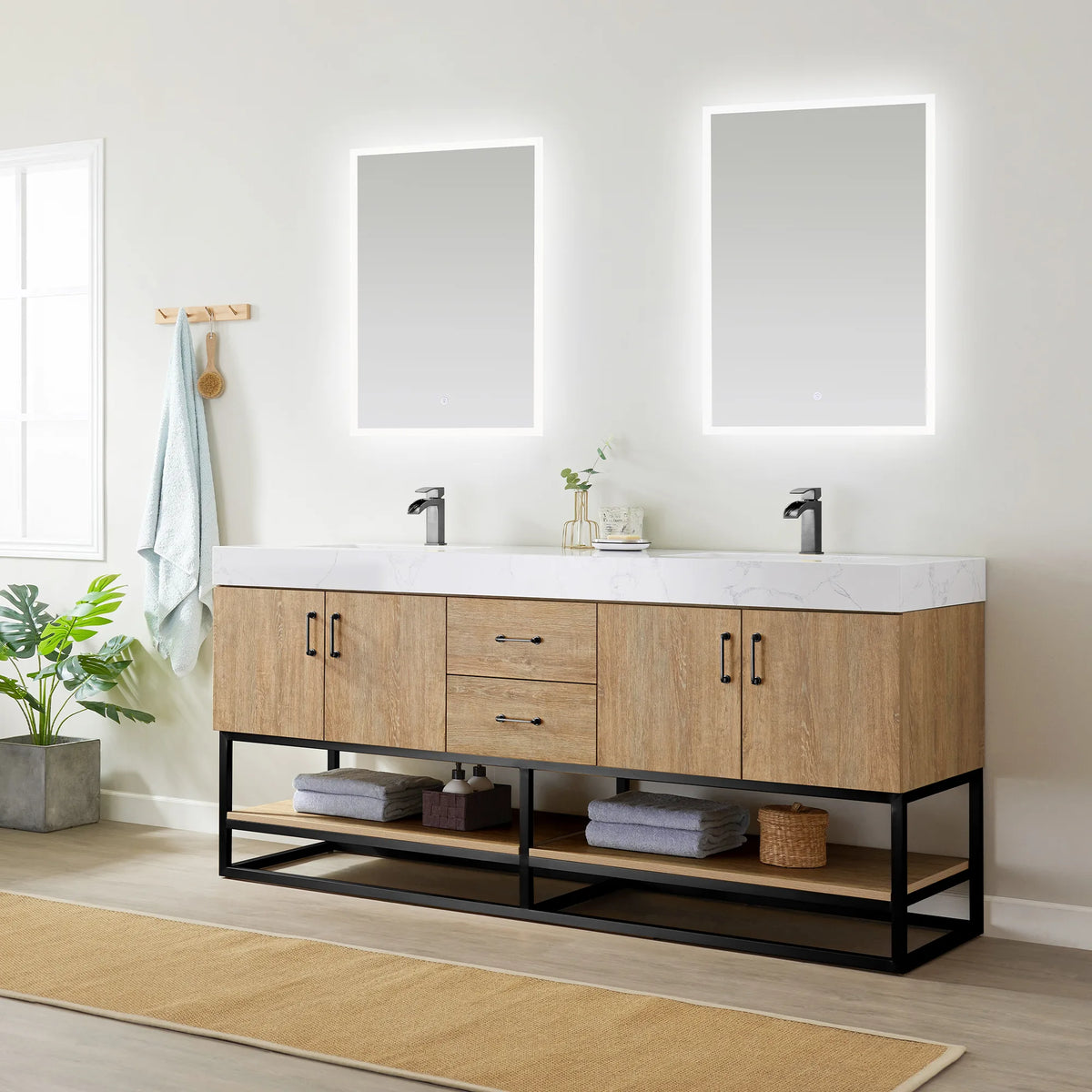 Wide room shot of the double vanity beneath two LED mirrors, with towels, baskets and a plant on a jute rug