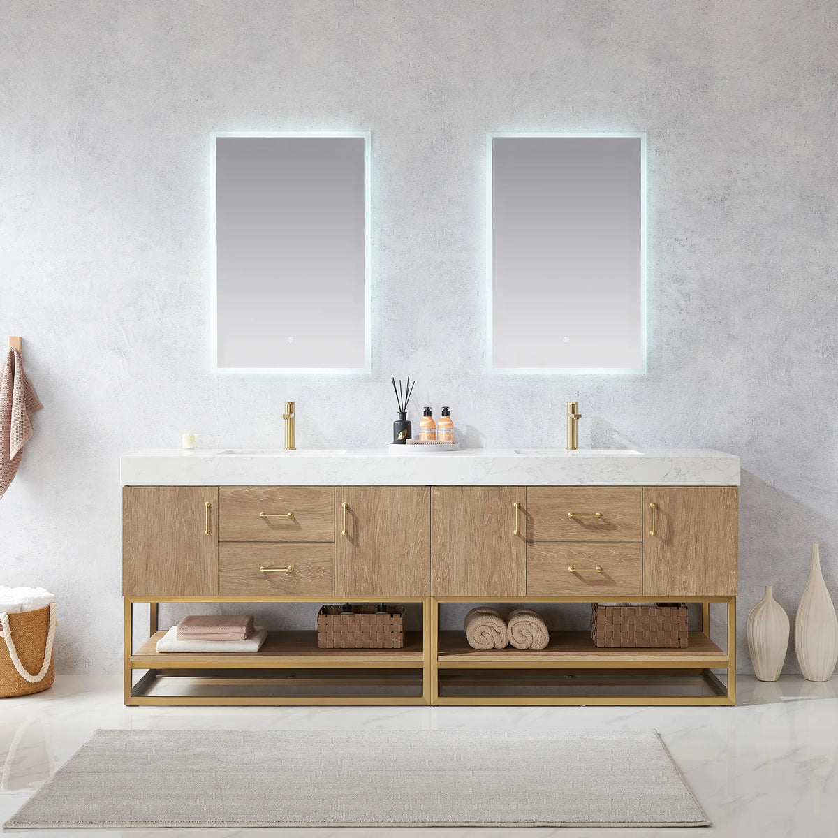 Straight-on room view of the double vanity under backlit mirrors, with a rug, basket and towels on the open shelf