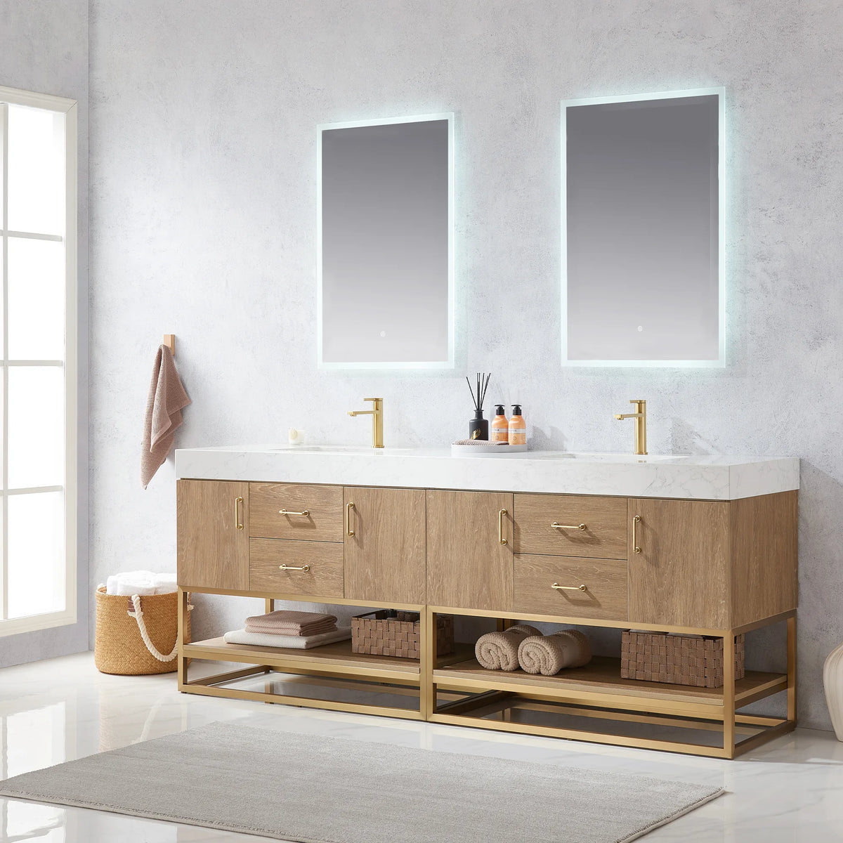 Angled room view of the double vanity beneath two LED mirrors, with diffuser on the counter, basket and rug