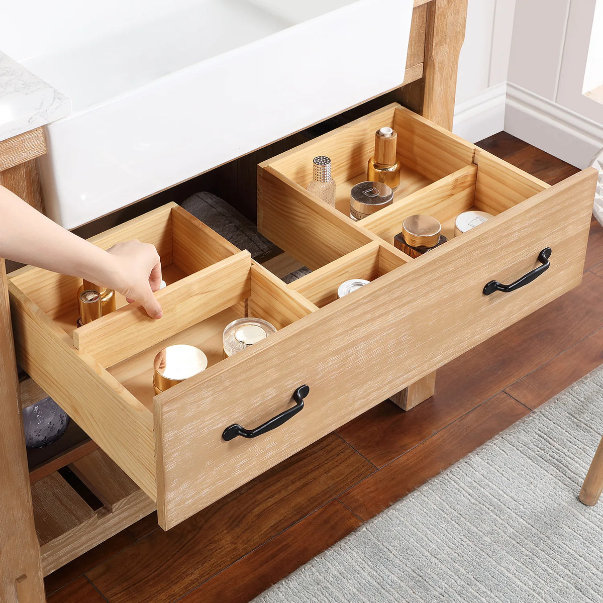 Hand adjusting wood dividers inside a pulled-out drawer