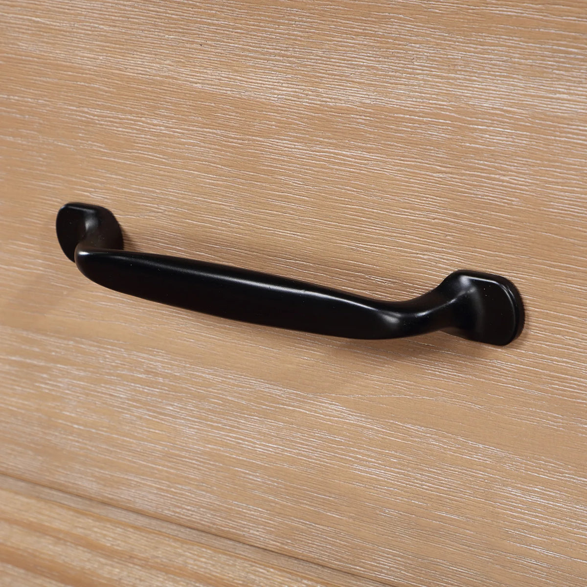 Rounded black drawer pull against grained Weathered Pine wood