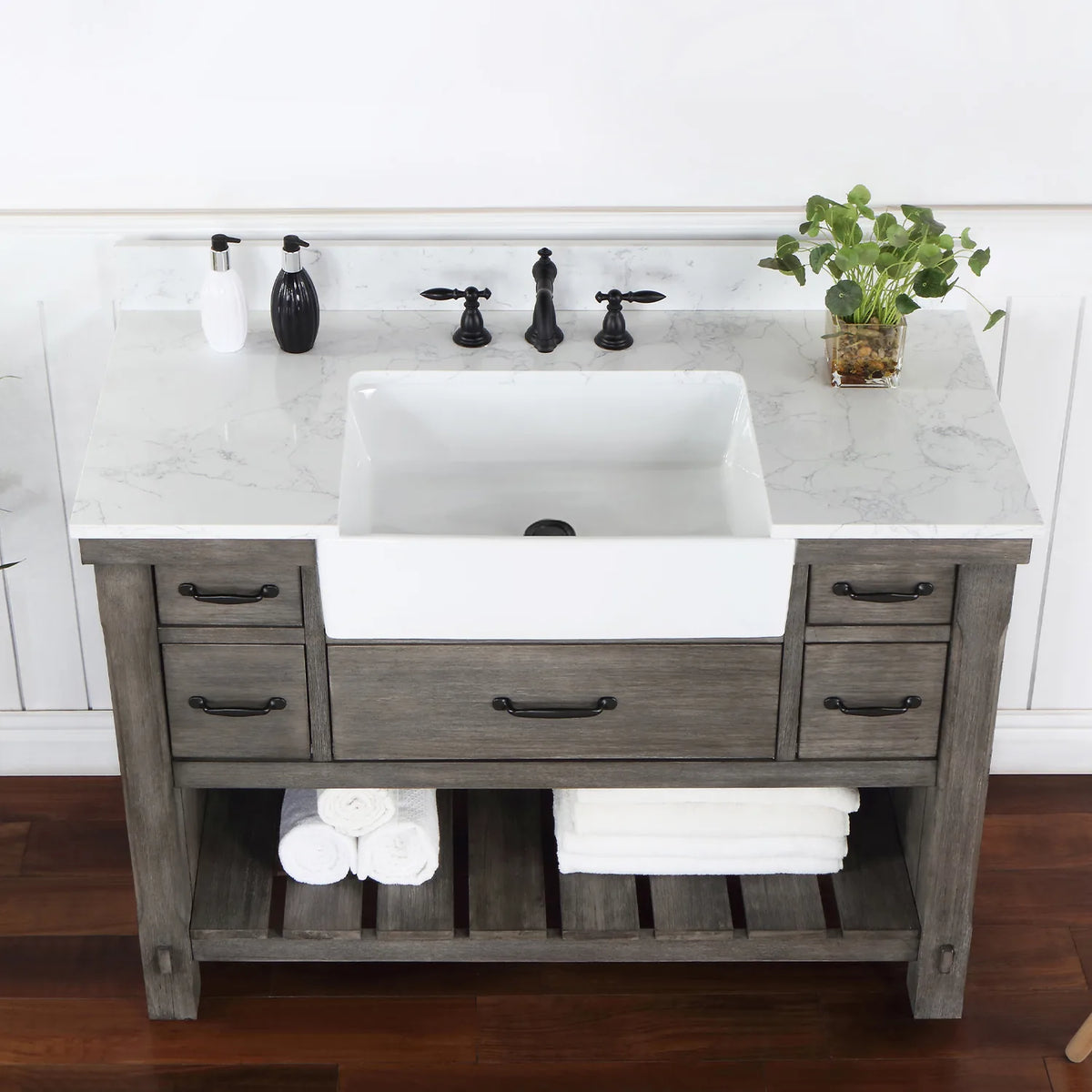 Overhead crop: stone surface, white basin, black pulls on the drawers below