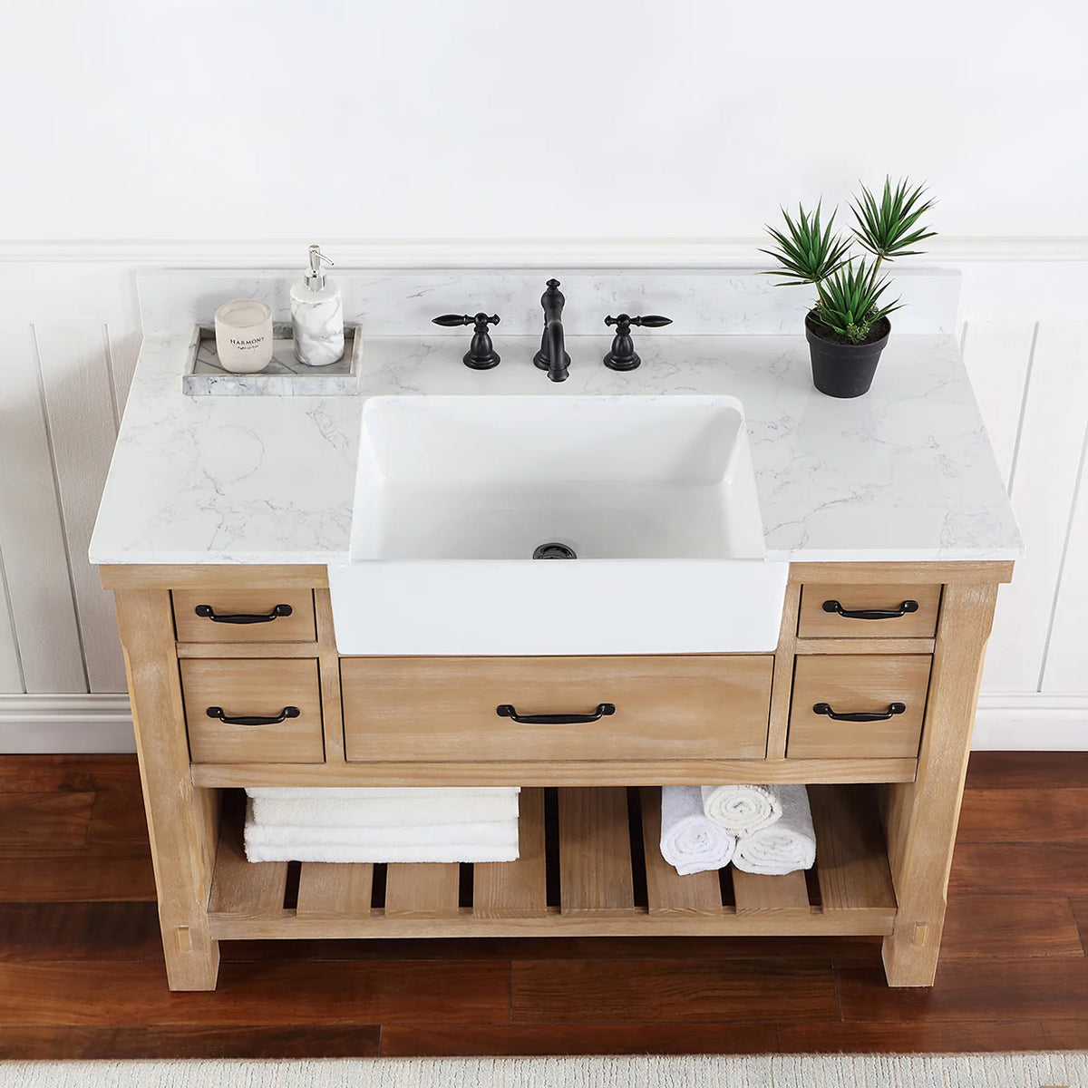 Overhead crop: stone surface, white basin, black pulls on the drawers below