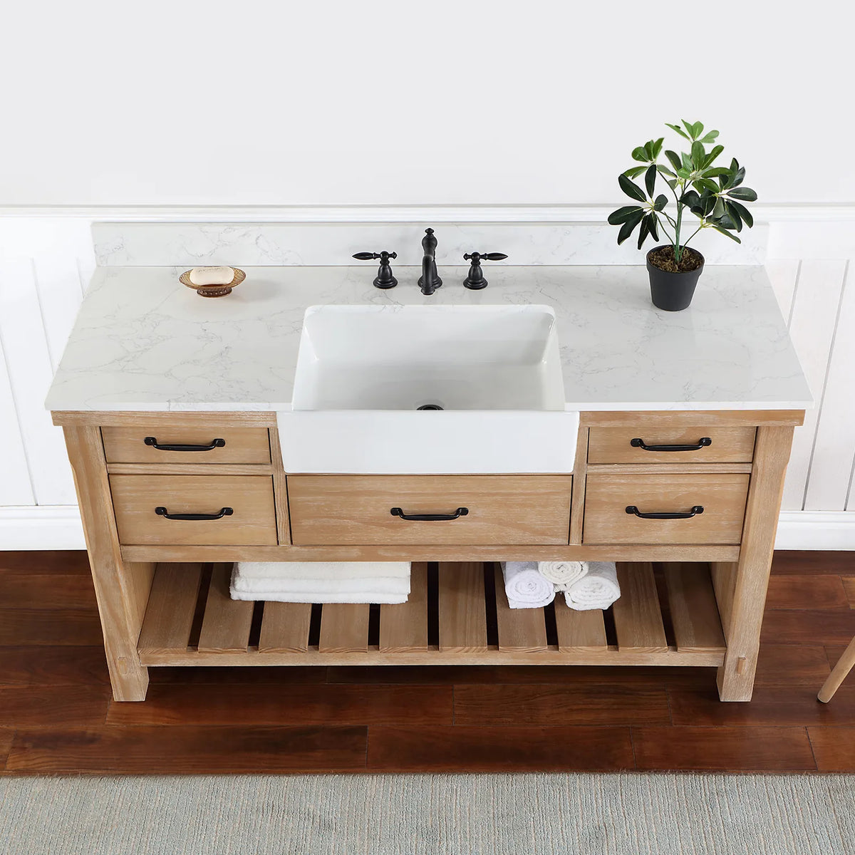 Overhead crop: stone surface, white basin, black pulls on the drawers below