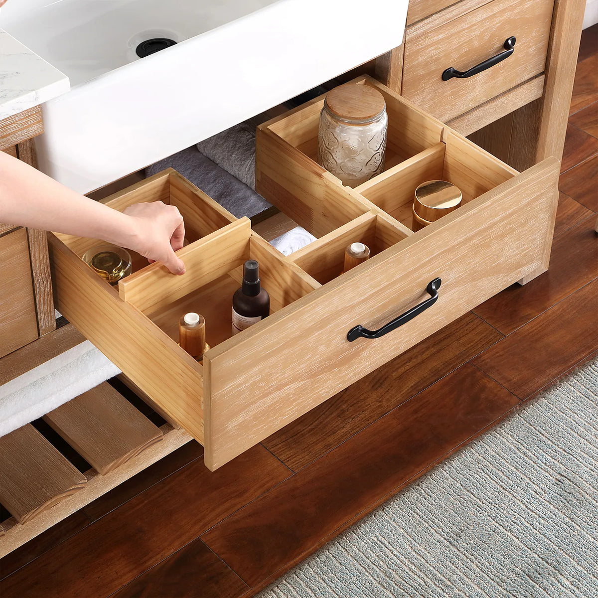 Hand adjusting wood dividers inside a pulled-out drawer