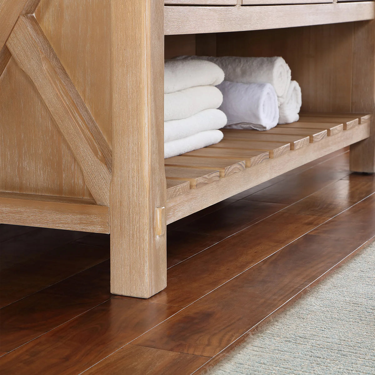 Chunky leg post with X-brace beside the slatted open shelving and rolled towels