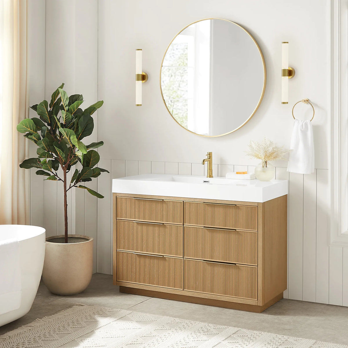 Bright bathroom scene with the 48-inch vanity under its matching circular mirror, gold wall sconces and a tall plant
