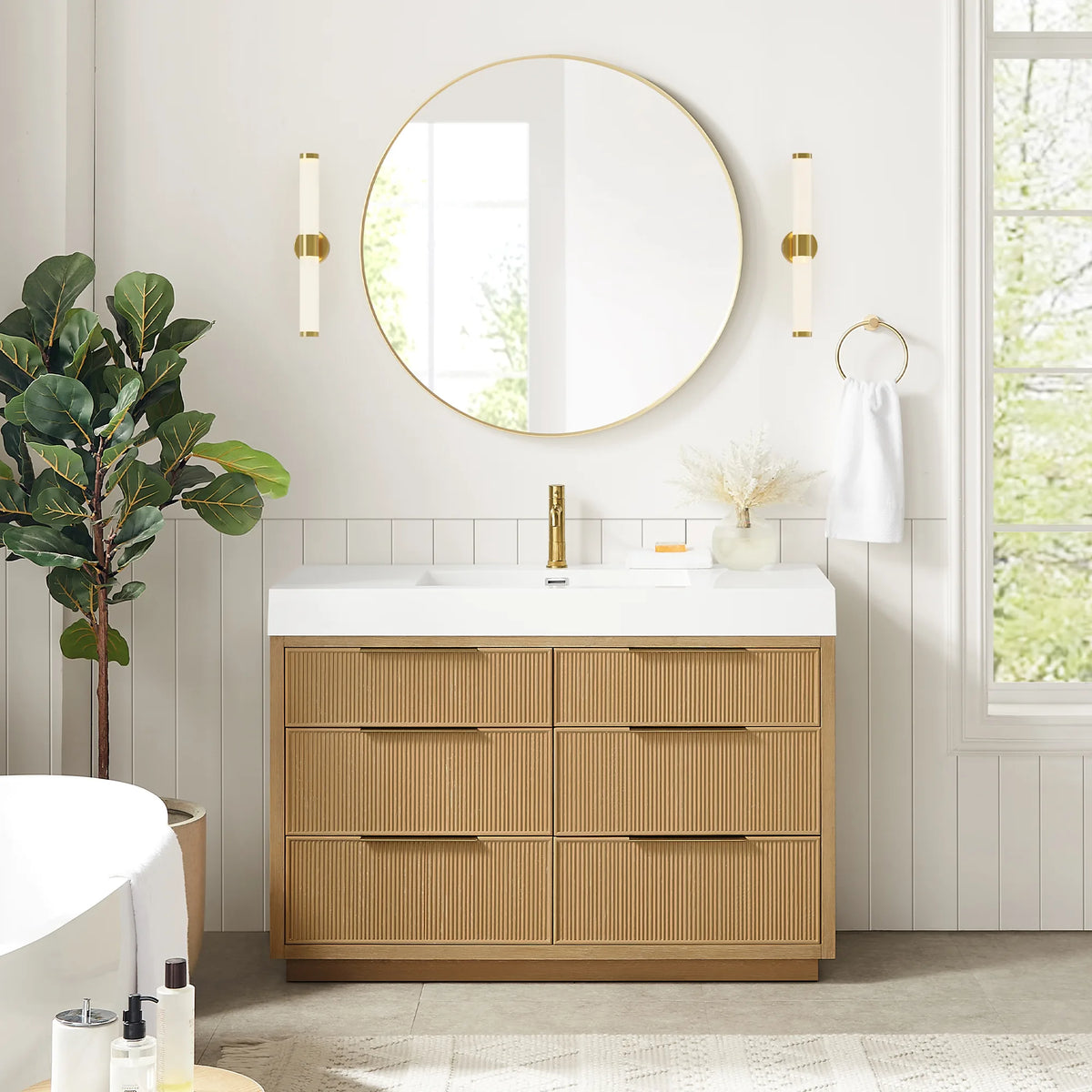 Room view of the 48-inch single vanity with a white top, circular gold mirror, wall sconces and a window at right