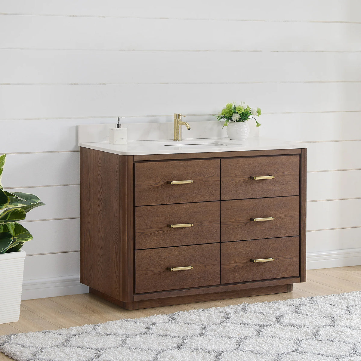 Bathroom scene, single vanity set at an angle against white shiplap, a tall plant beside it