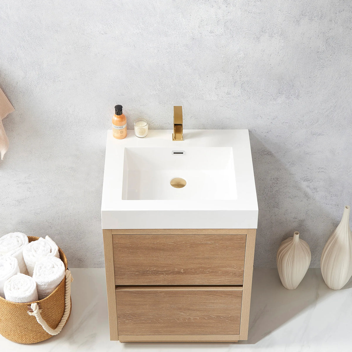 Looking down at the integrated white sink on the vanity, small bottle and candle on the top