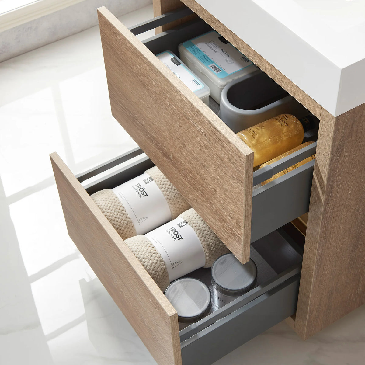 Close-up of open drawers filled with toiletries, towels and jars, gray drawer sides