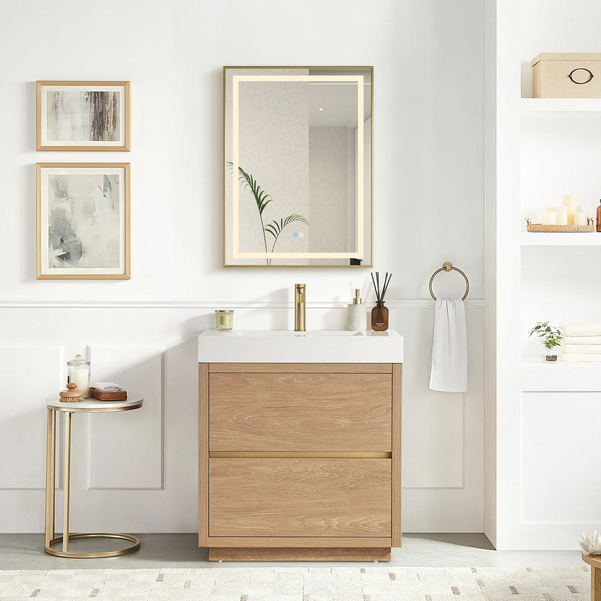 Wide shot of vanity and LED mirror in a white bathroom, with a plant beside the mirror and decor at right