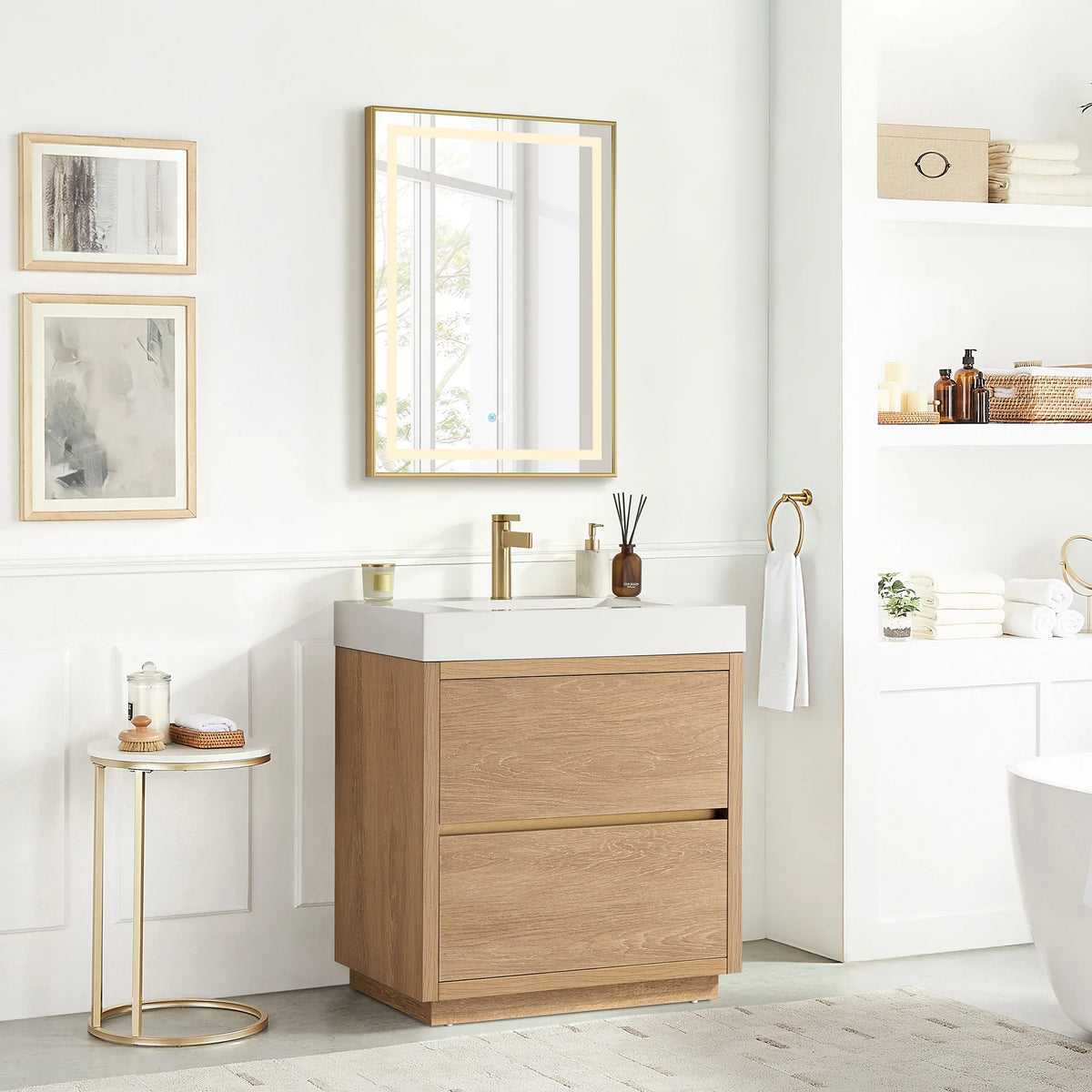 Room scene of the 30 inch vanity with a mirror, art prints, towel ring and a gold side table