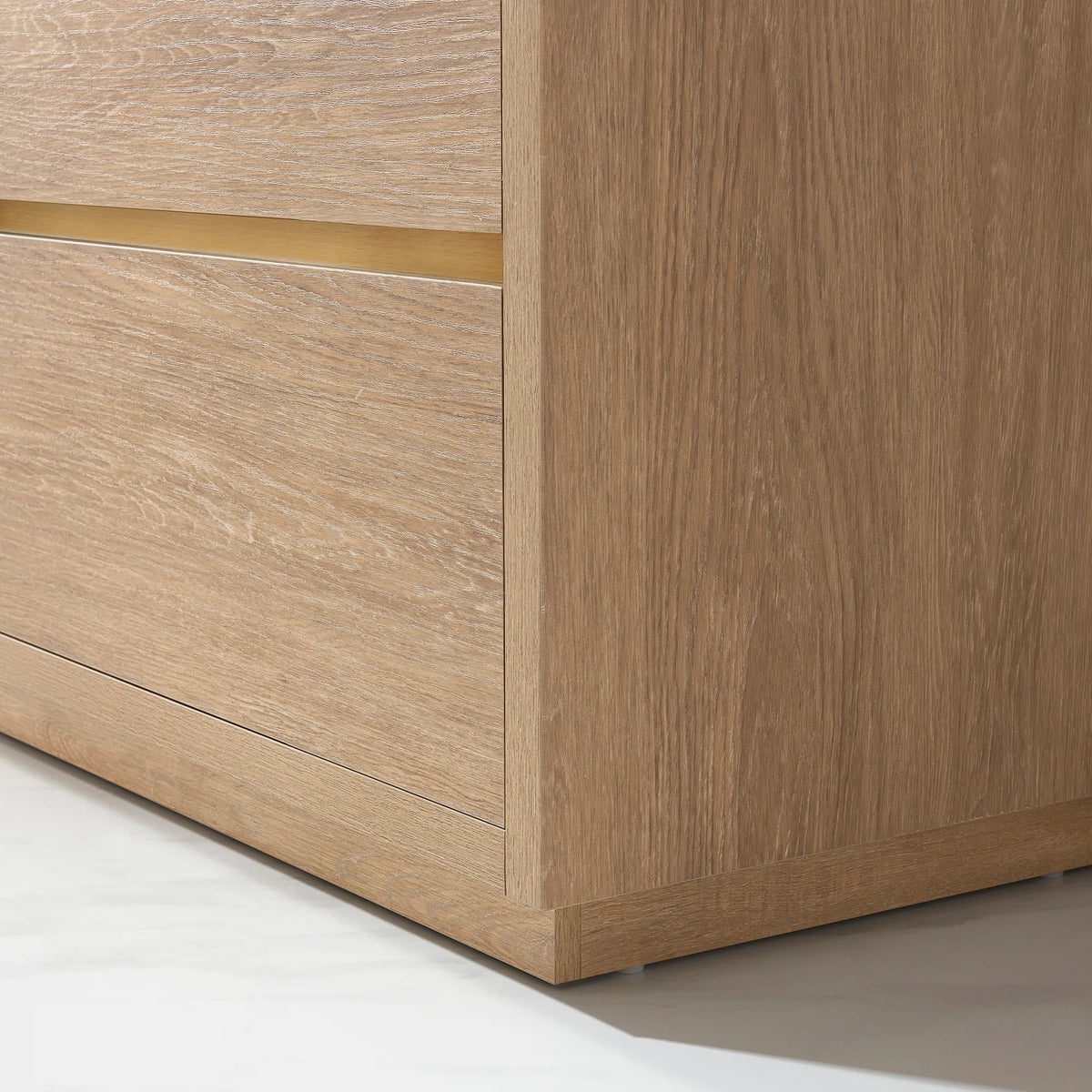 Close-up of the oak front, brushed gold pull and plinth base of the vanity