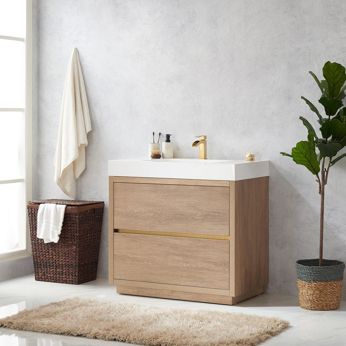 Angled view of the vanity beside a window, hanging towel, wicker hamper and plant