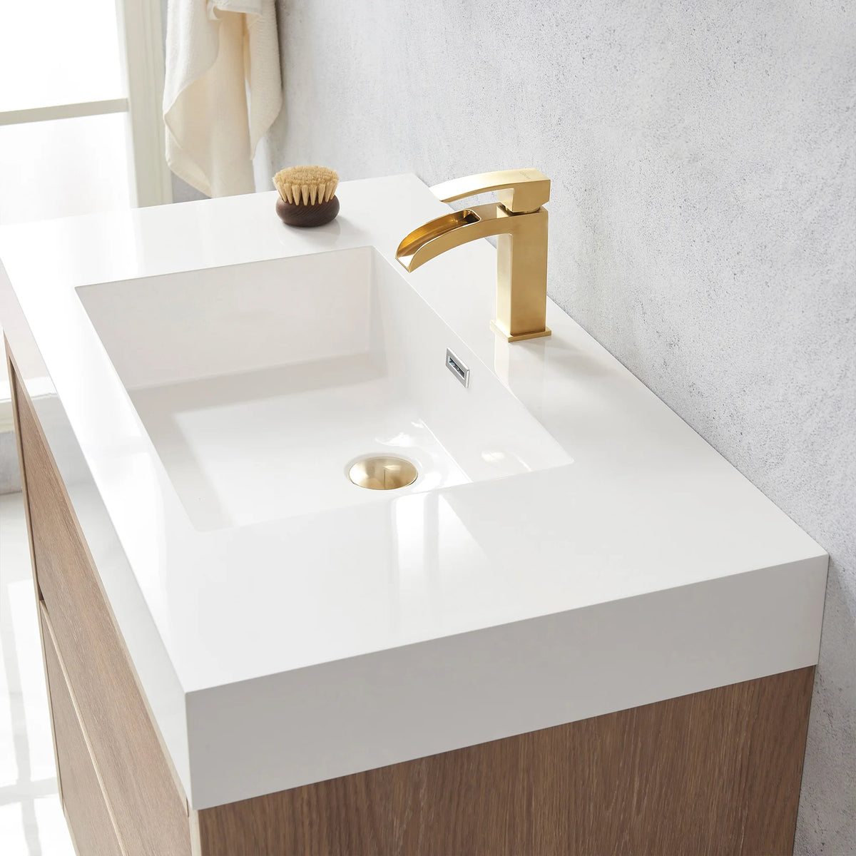 Close-up of the white integrated sink and drain with a small brush resting on the top
