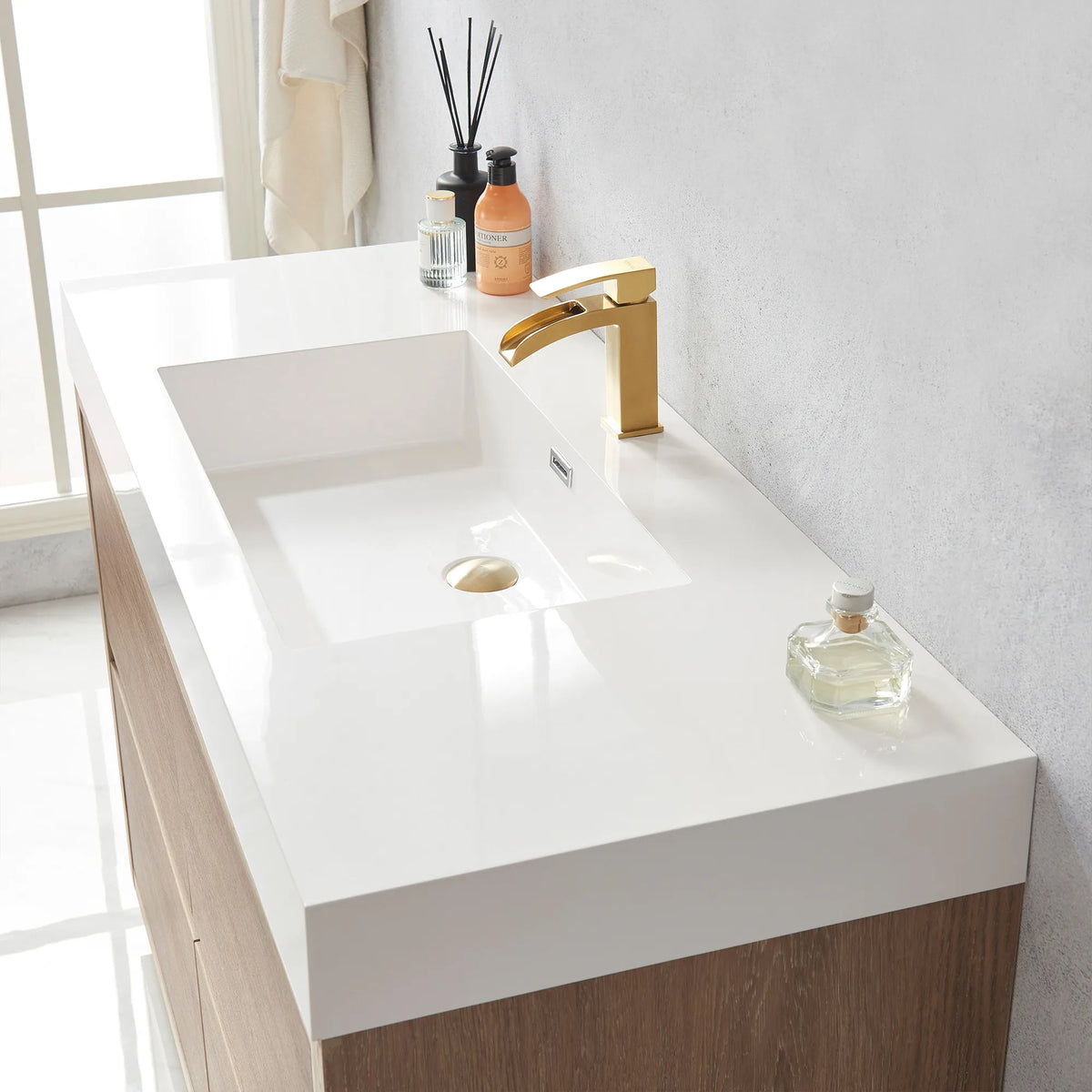 Close-up of the white integrated sink with drain, diffuser and bottle on the vanity top