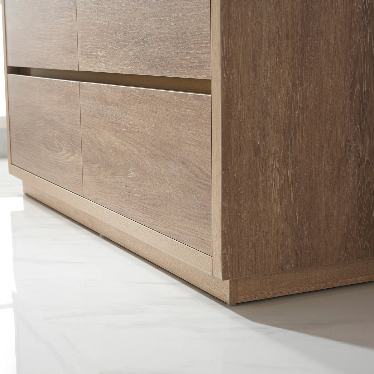 Low-angle close-up of oak front panels and plinth base on a white floor