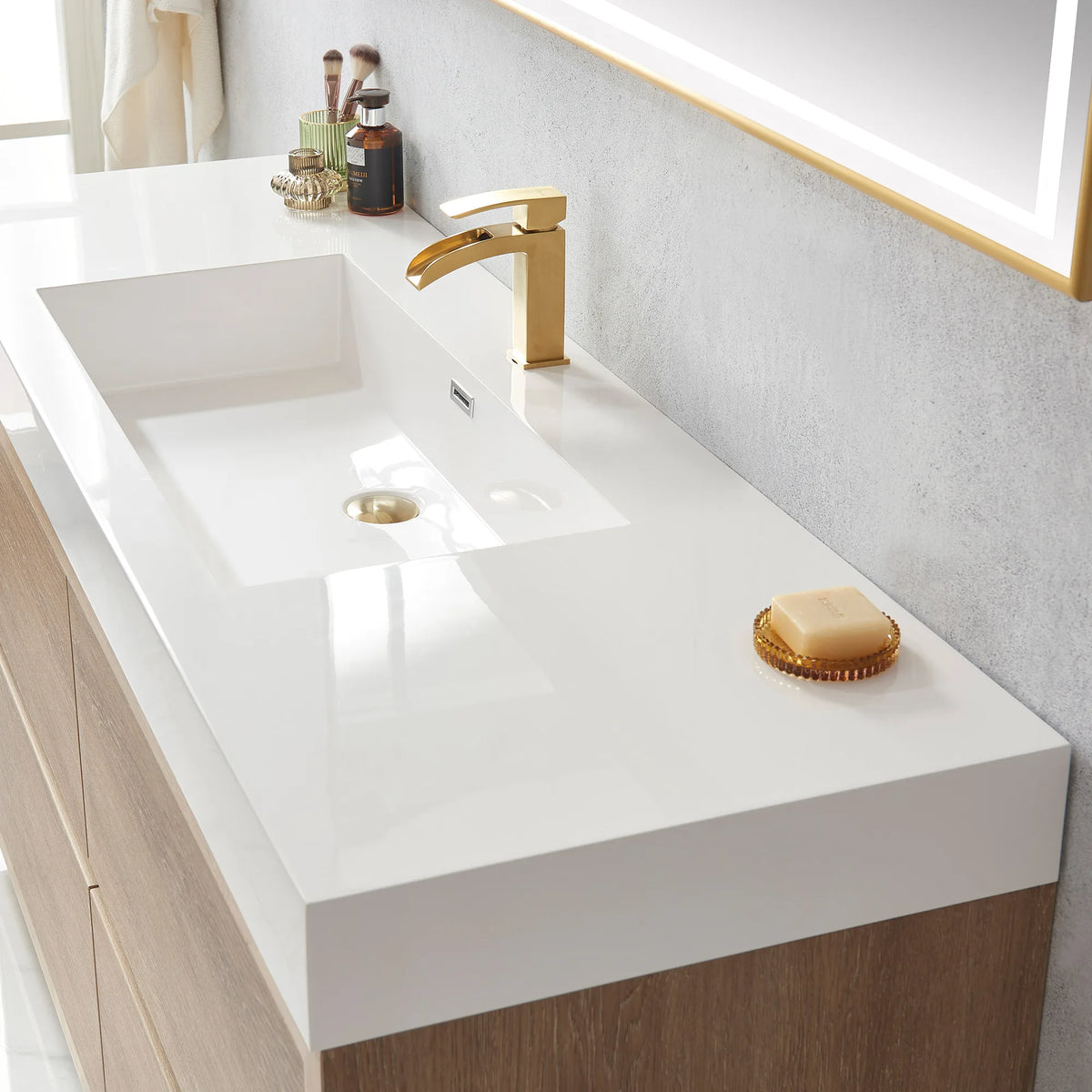 Close-up of the white integrated sink with drain and gold soap dish, mirror frame at top corner