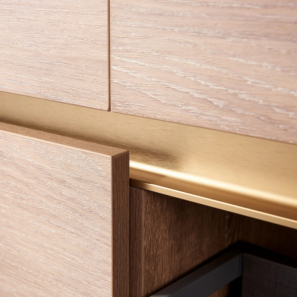 Extreme close-up of the brushed gold pull channel and oak grain on the front