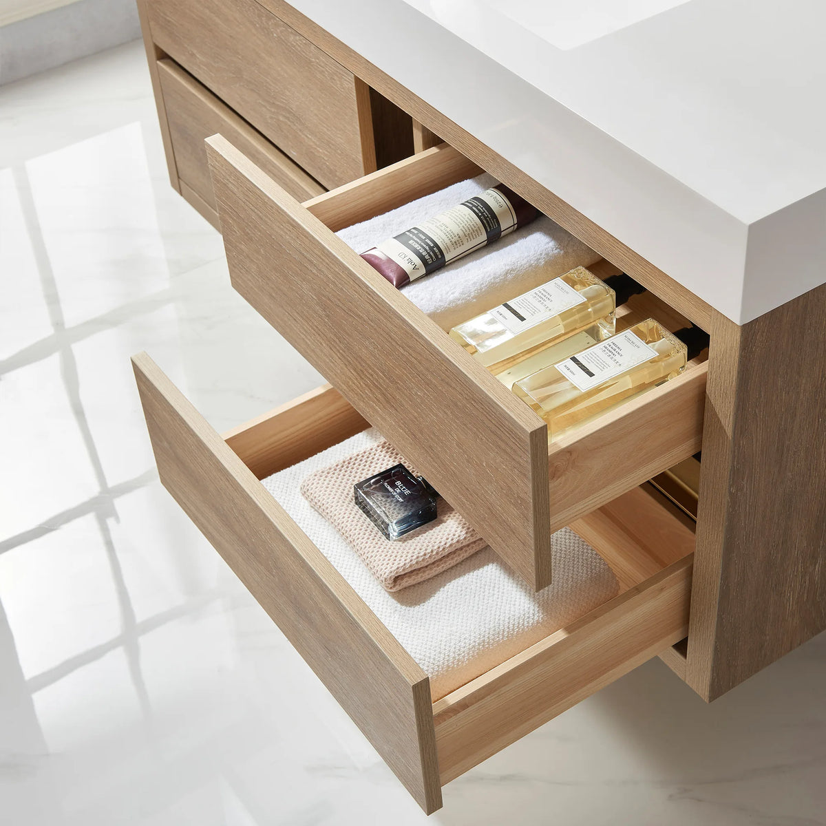 Look into open drawers holding oils, a brush and a towel, with white top overhead