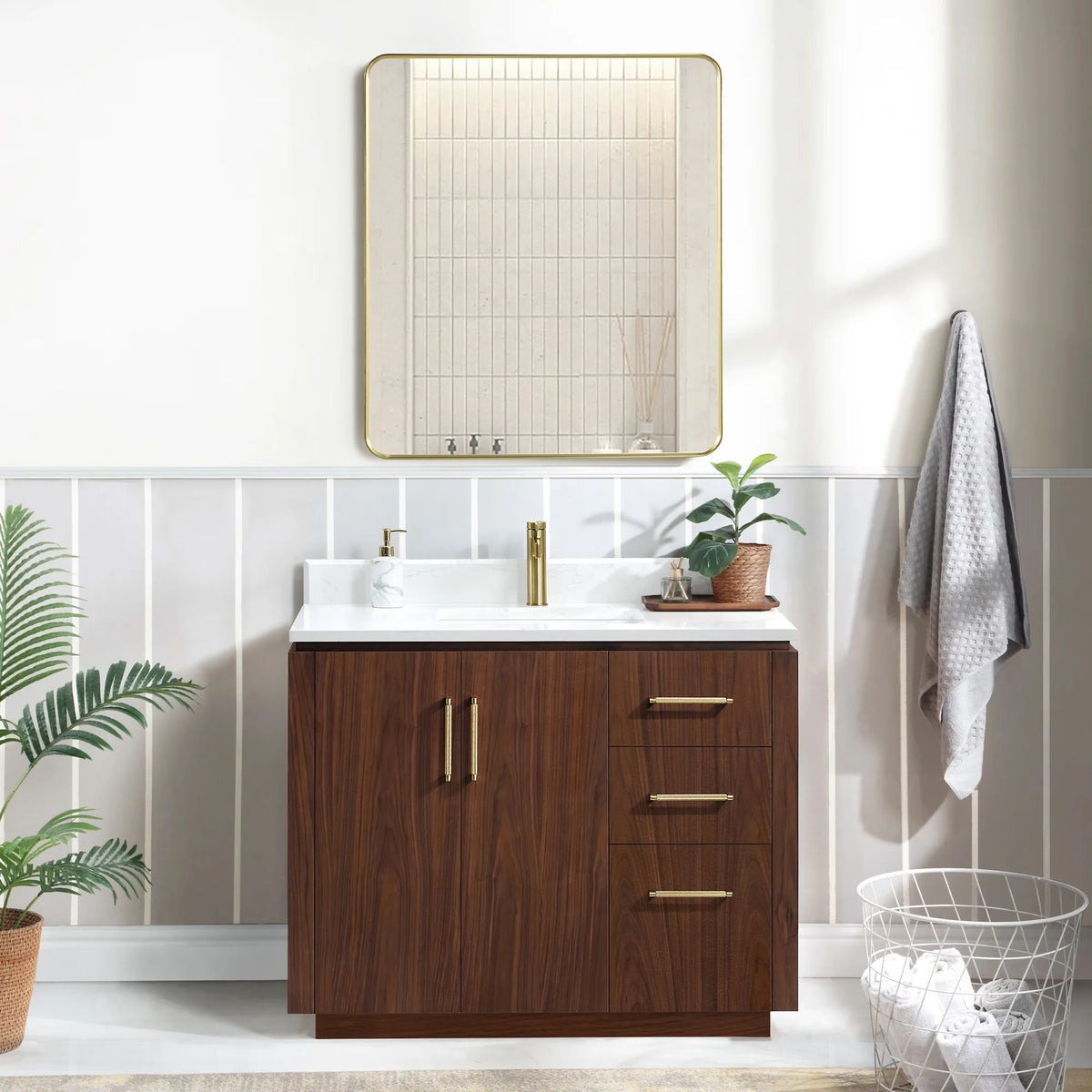 Bathroom scene with a 42 inch vanity, framed mirror above, a wire basket on the floor and a plant by the sink