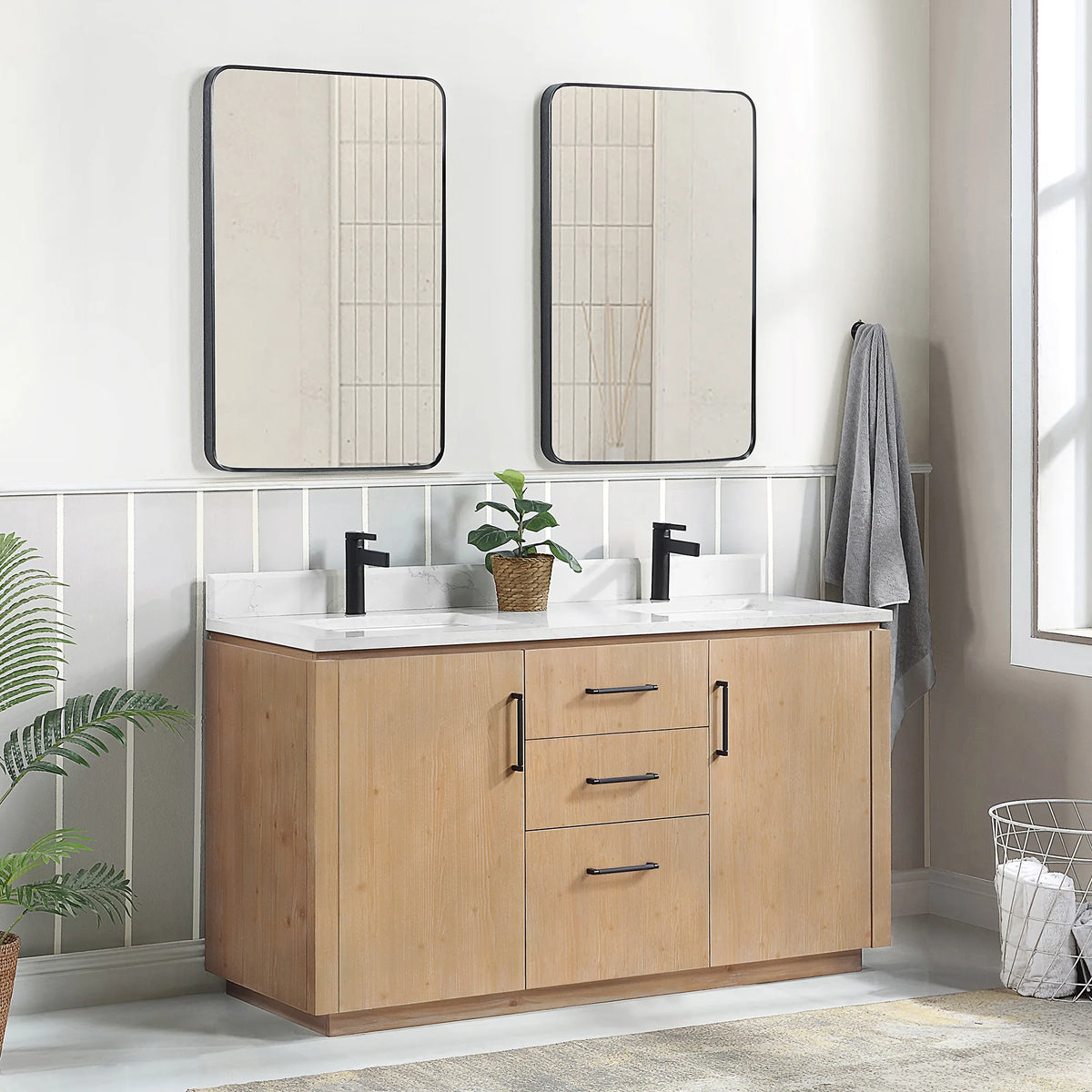Wider room view of the double vanity at an angle with tall mirrors, plant and towel