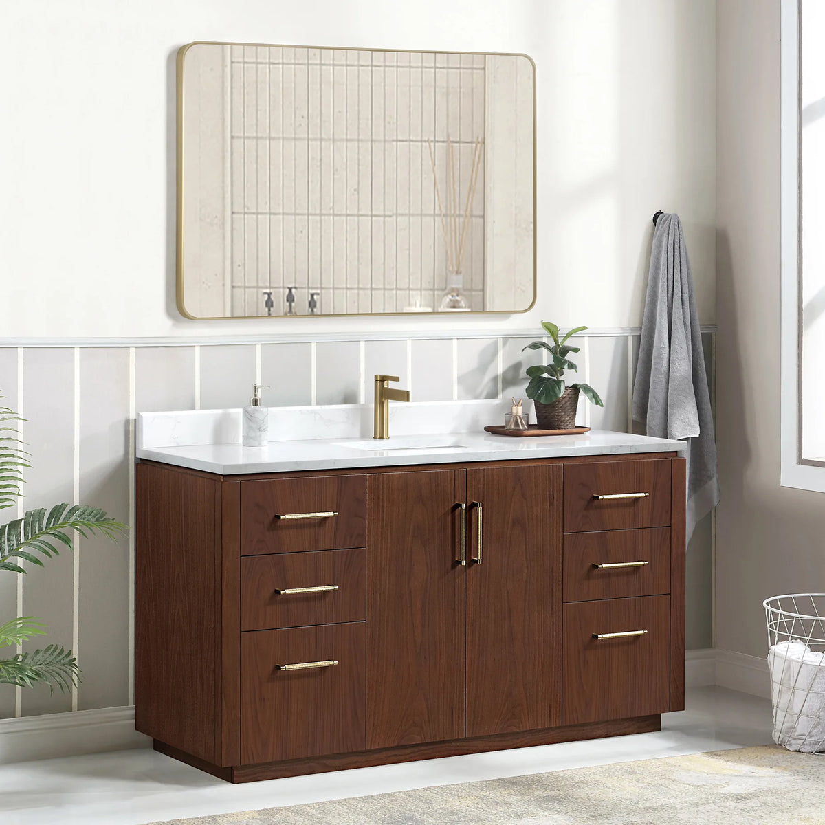 Angled room scene of the vanity with mirror, wire basket at the right edge and a soap dispenser on top
