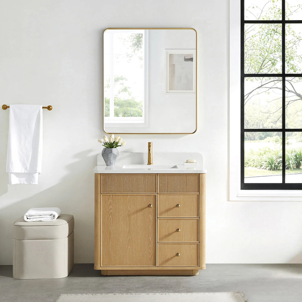 Matching rounded-rectangle gold mirror above the Washed Ash Grey vanity in a bathroom with a black-framed window