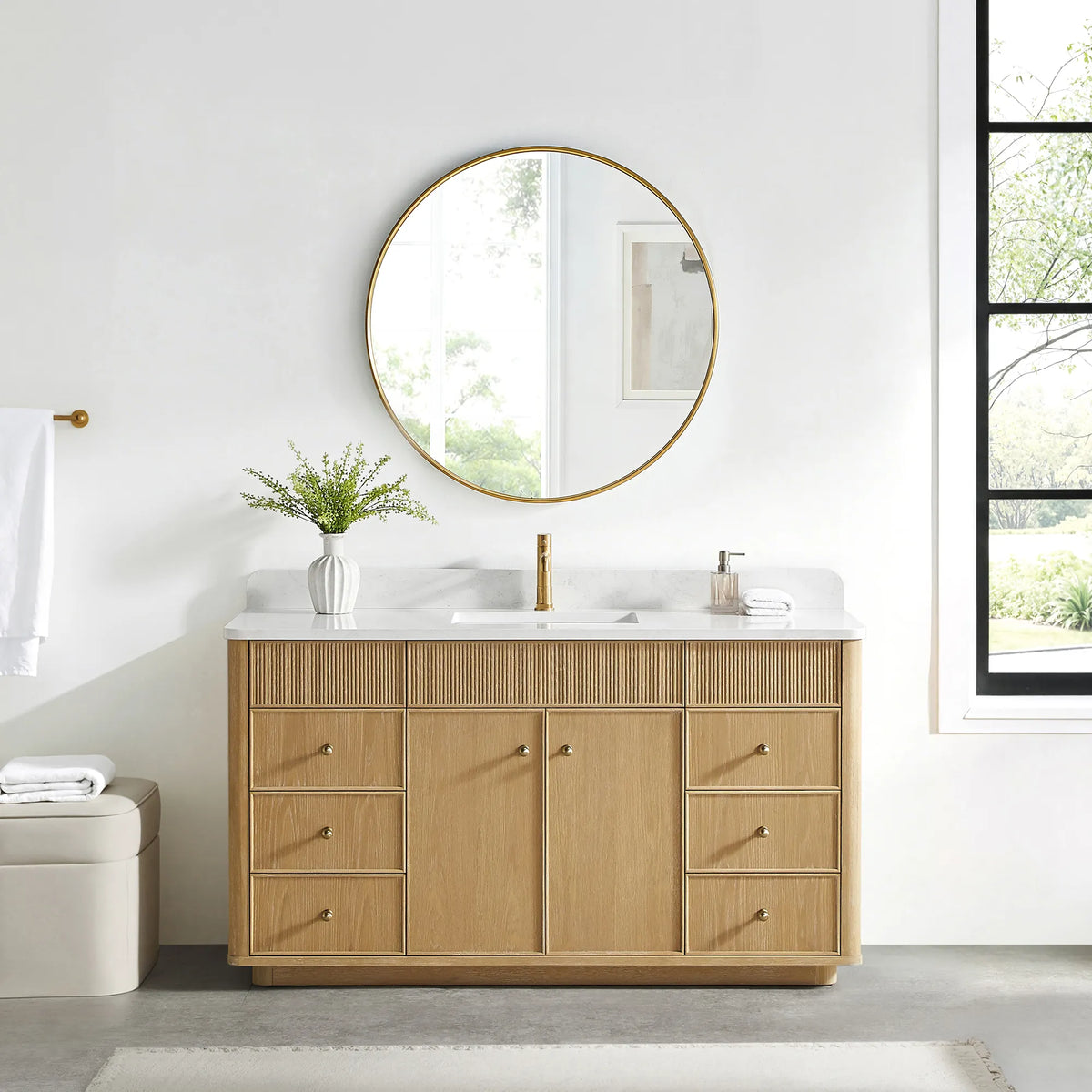 Matching round gold mirror above the Washed Ash Grey vanity in a bathroom with a black-framed window