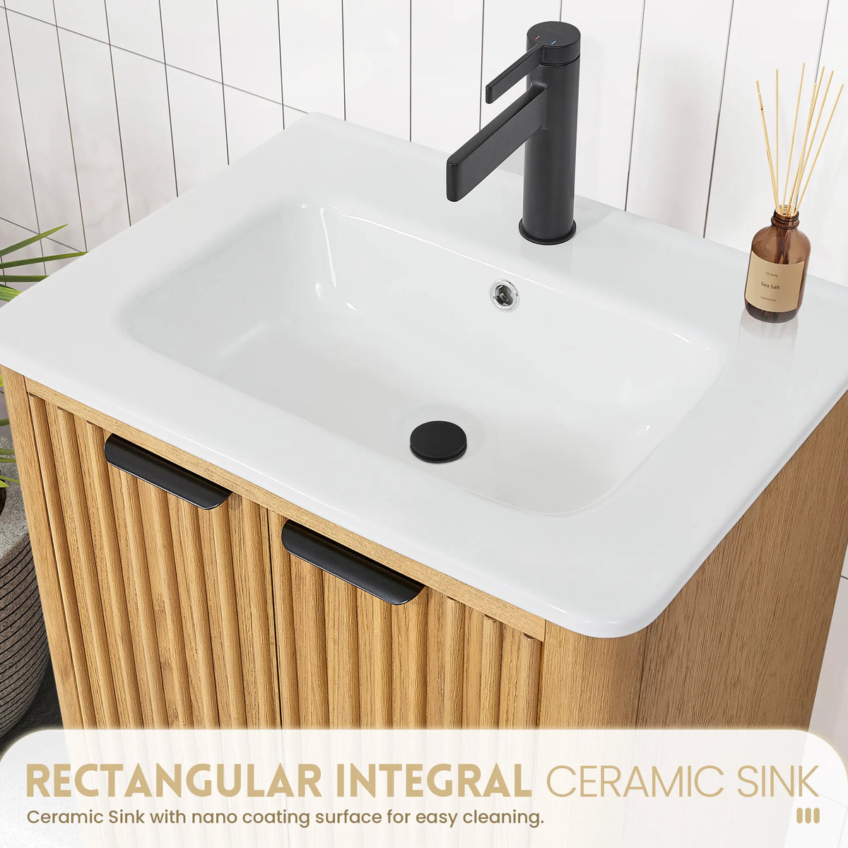 Callout on the one-piece white ceramic basin of the 24-inch vanity, a black faucet and reed diffuser beside it