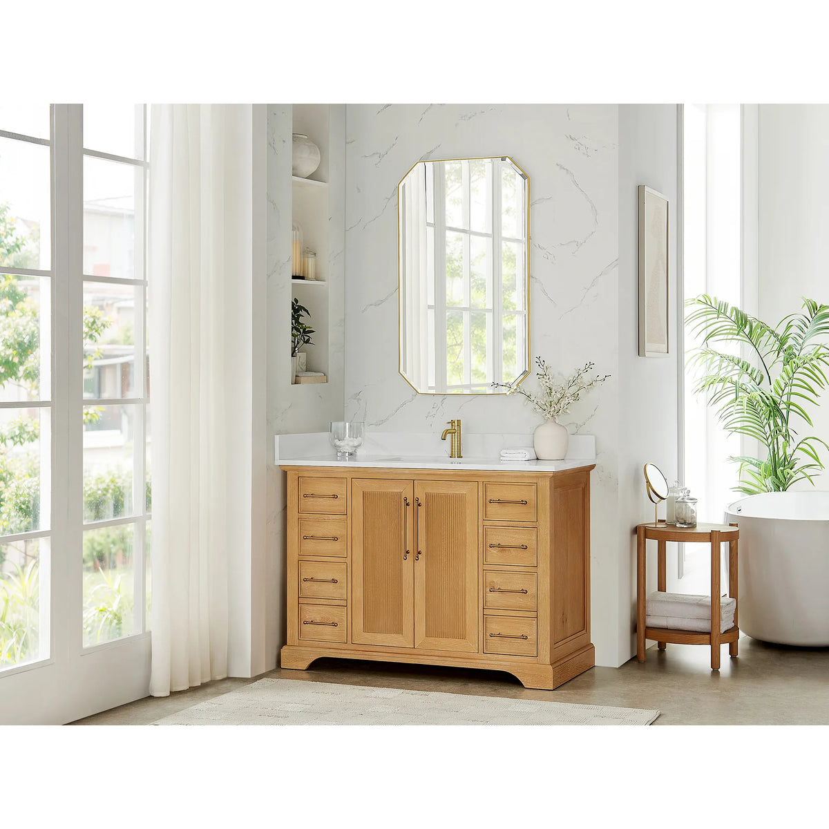 Wide room scene with a 48 inch single vanity and a round wooden side table, marble-look walls and tall windows