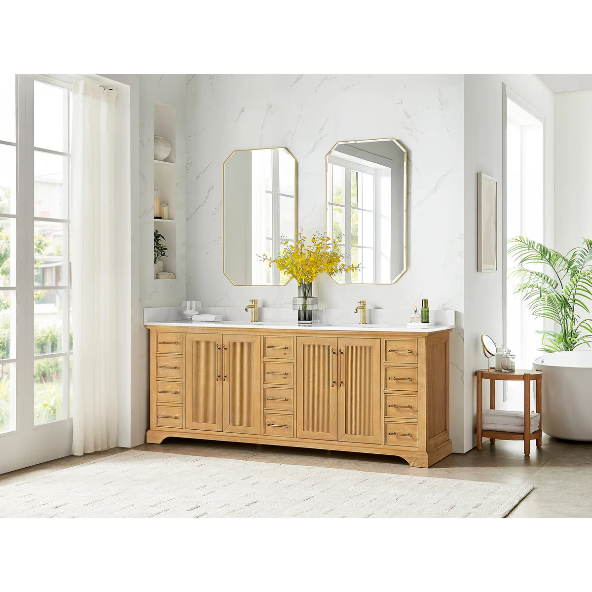 Wide room scene with an 84 inch double vanity and a round wooden side table, marble-look walls and tall windows