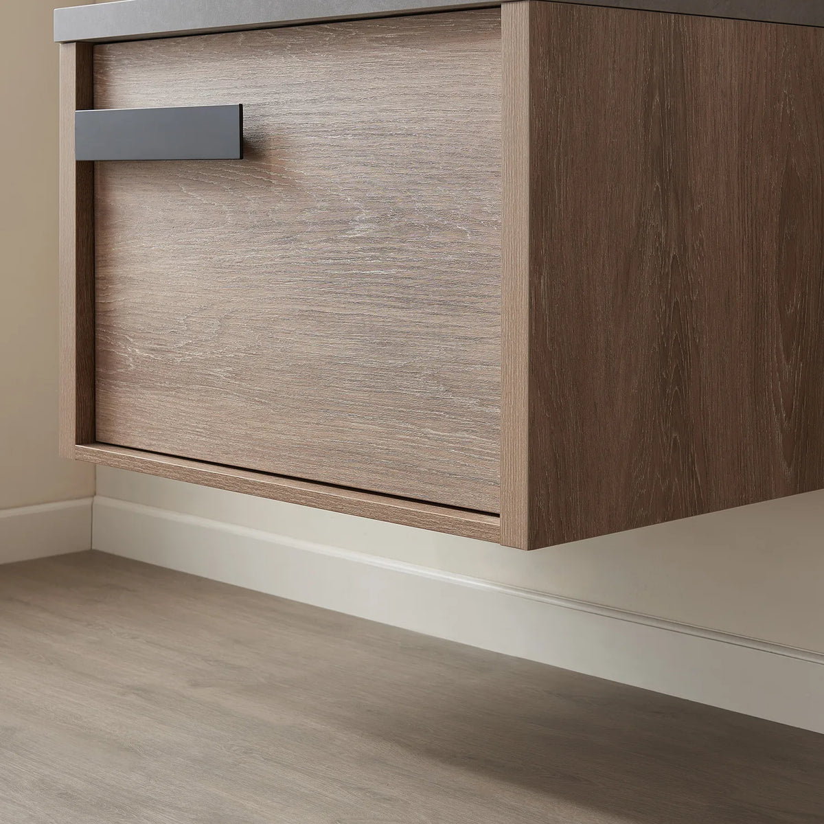 Wall-hung cabinet corner, matte black pull near the top left