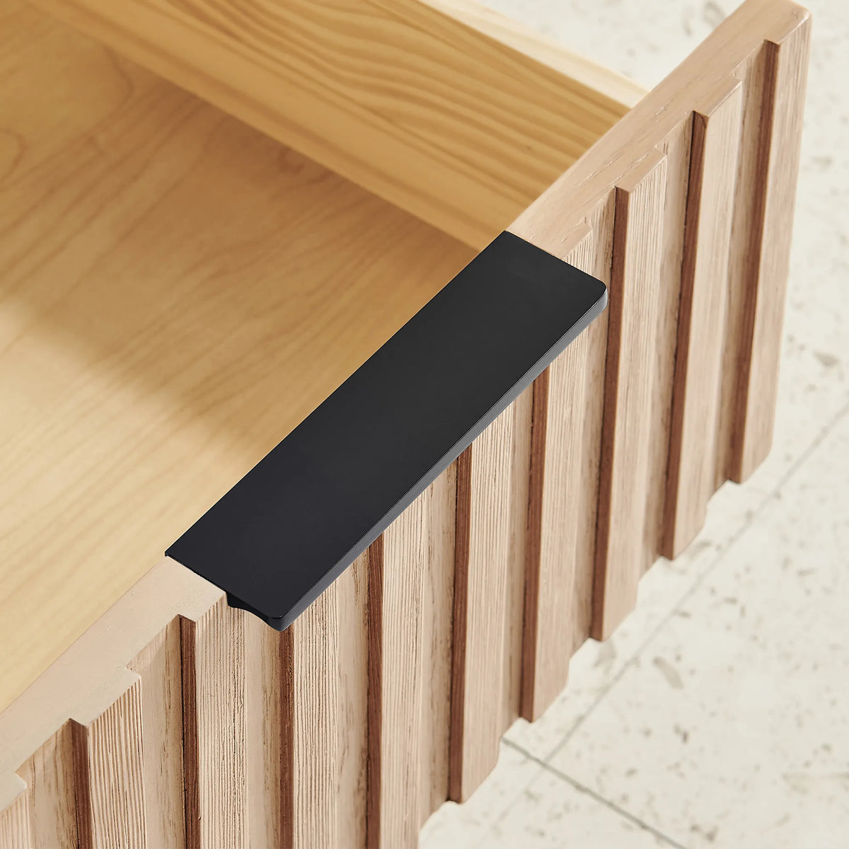 Macro view of a black flat handle and ridged wood front on the 72-inch double vanity