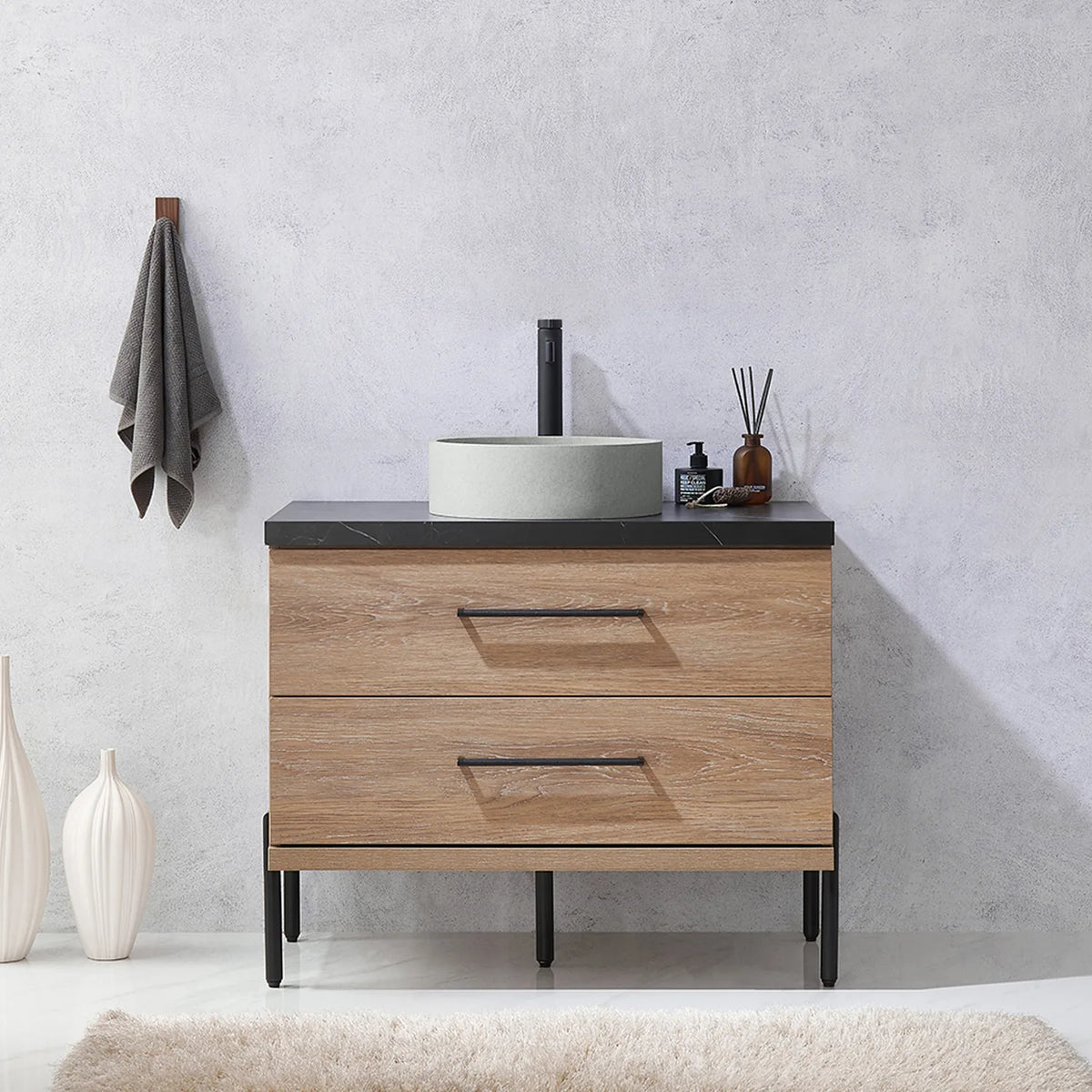 Pale plaster wall, white vases and a hanging towel behind the oak vanity on black legs