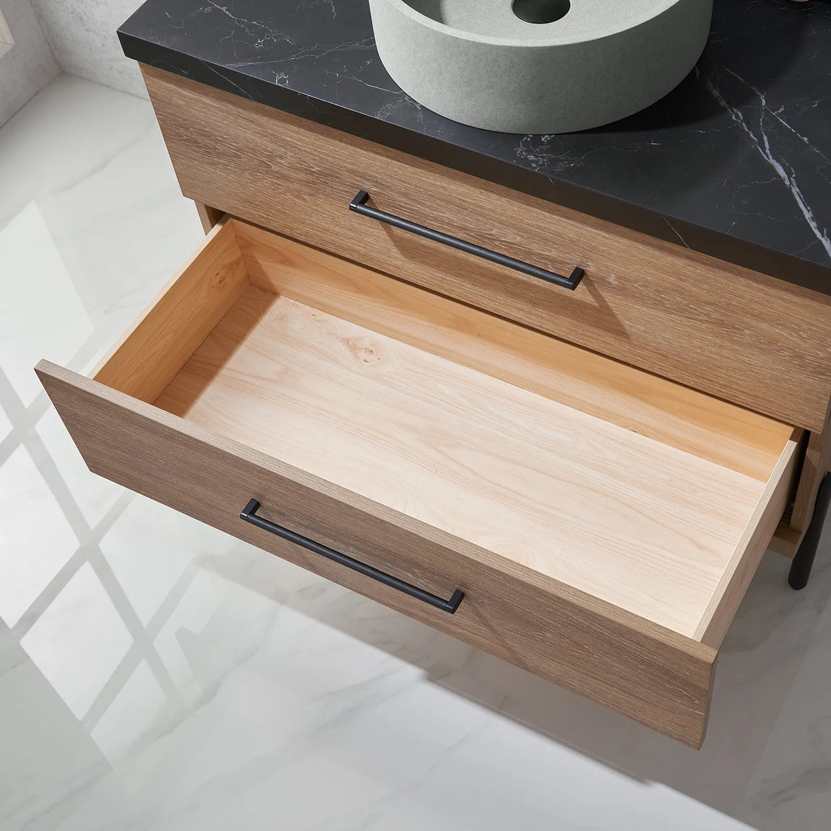 Bare drawer box in light wood, pulled out beneath a bar-handled drawer front