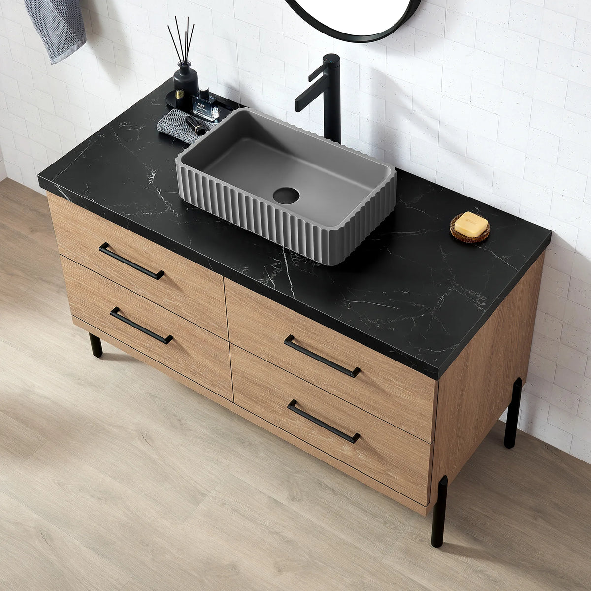 Looking down on the black veined top, a tall faucet and the rectangular ribbed concrete vessel