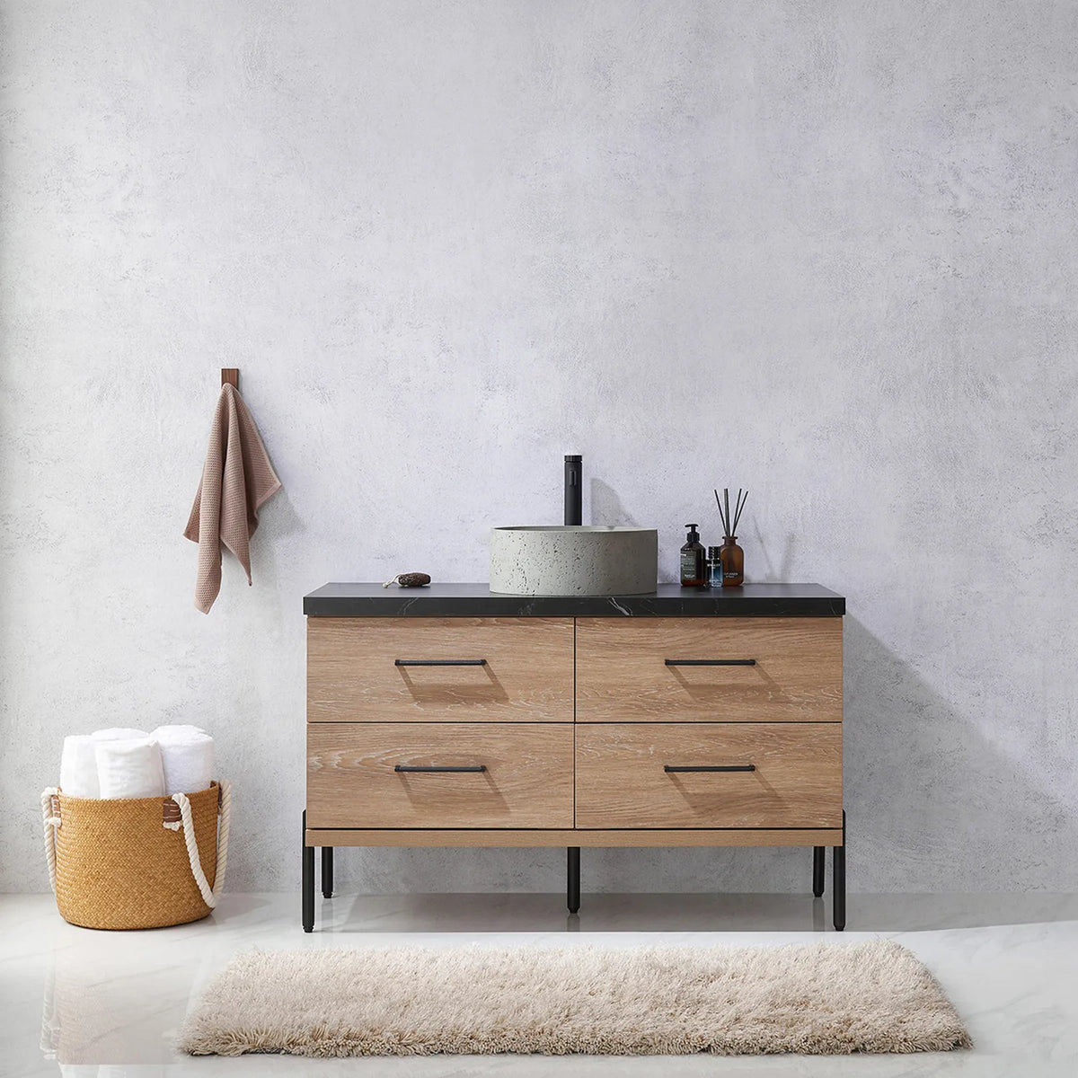 Pale plaster wall, white vases and a hanging towel behind the oak vanity on black legs